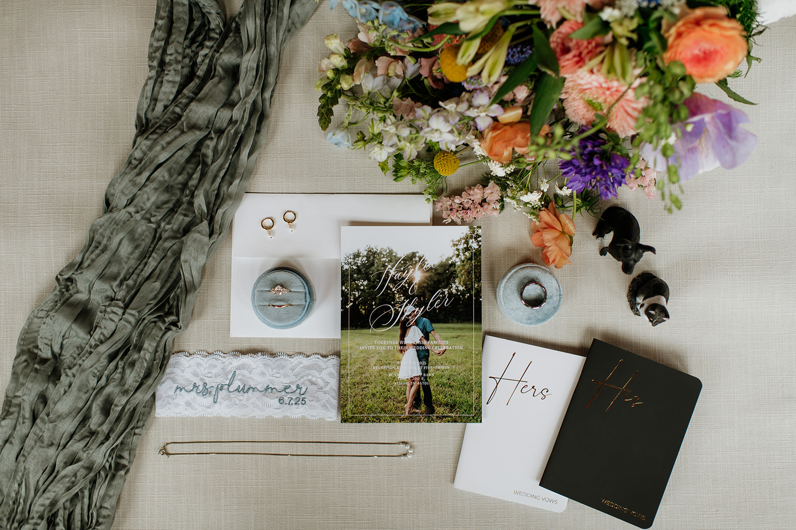 Wide shot of summer wedding details with florals, invites, his and her vow books, rings, and more from a Midwest wedding in Indiana