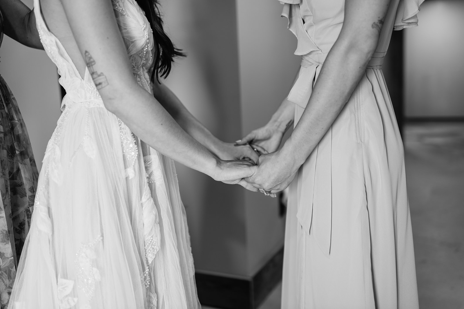 Close up black and white photo of two sisters holding hands as one gets ready for her wedding day