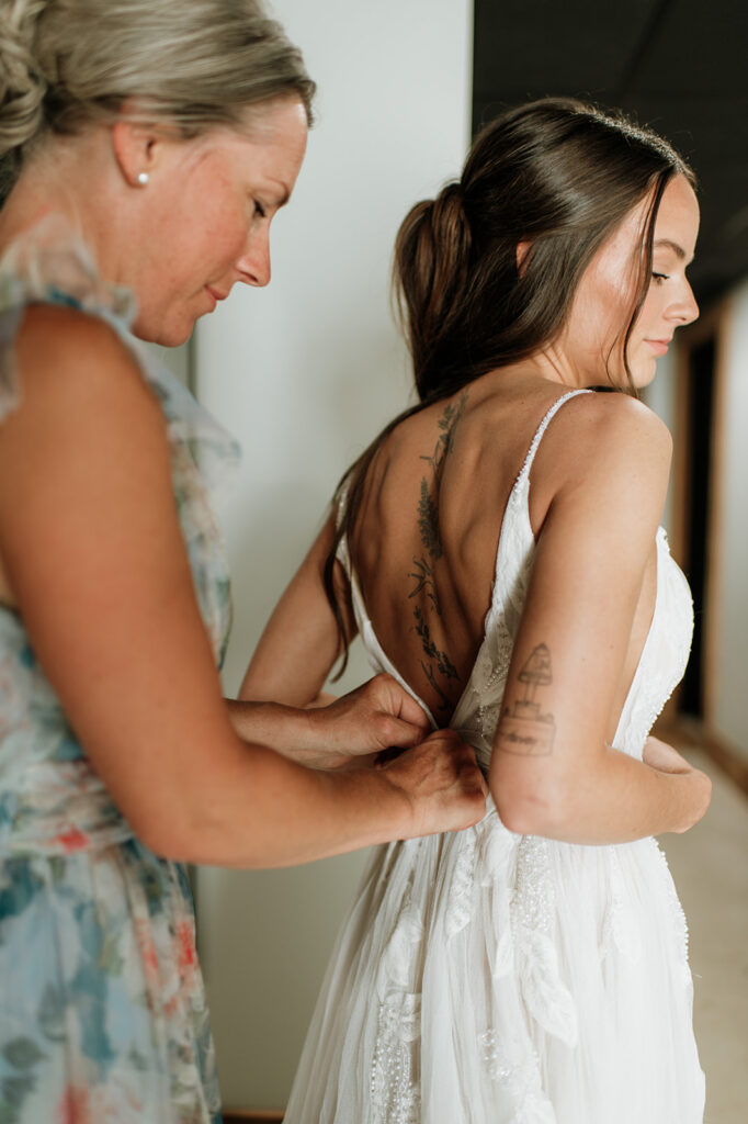 Close up of the brides mother zipping up her wedding dress