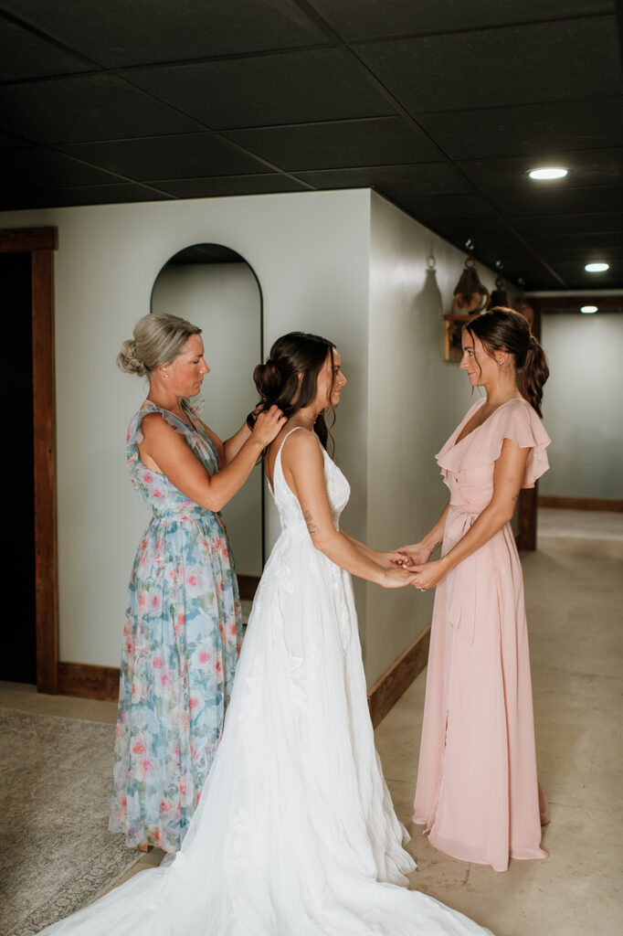 Bride getting ready with her mother while holding her sisters hands