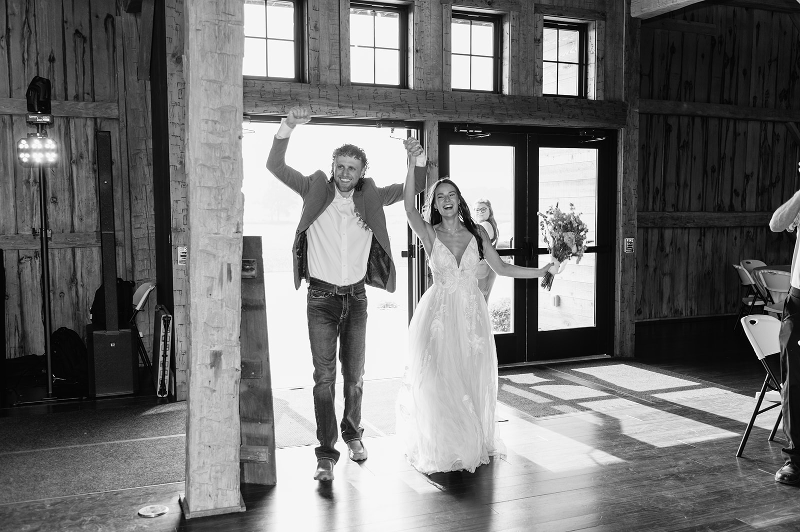 Black and white photo of a bride and groom entering their 5C Farms wedding reception - Premier Indiana barn wedding venue