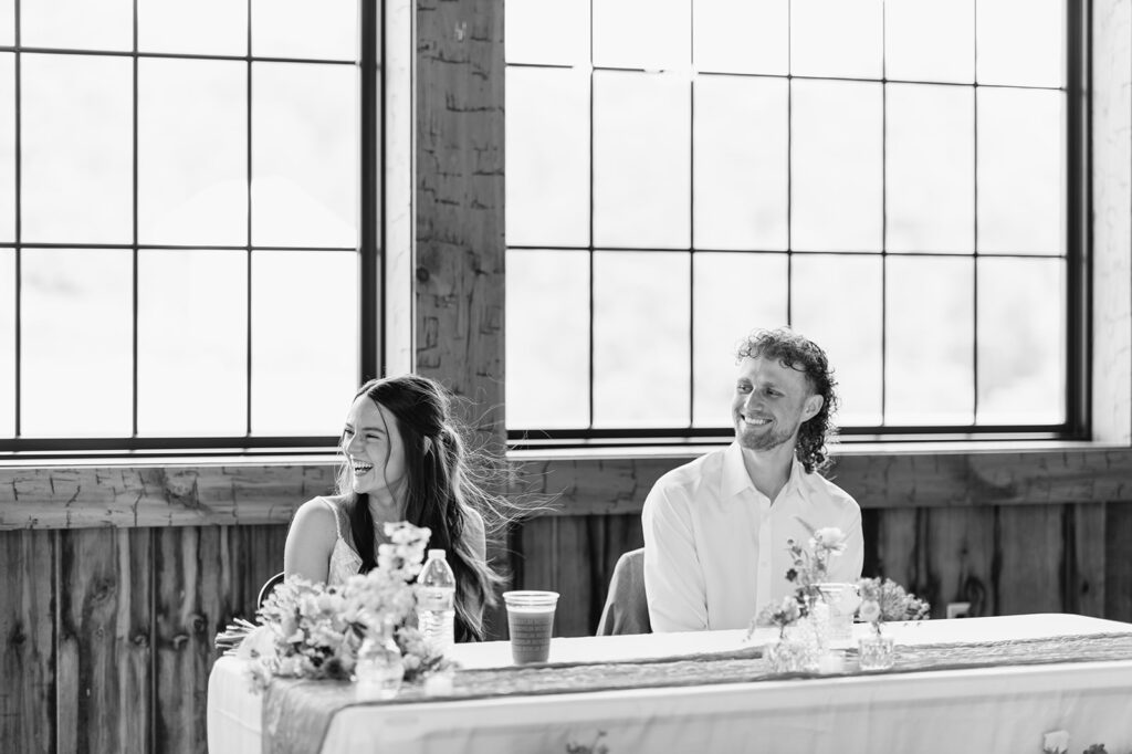 Black-and-white photo the bride wipes and groom laughing during speeches