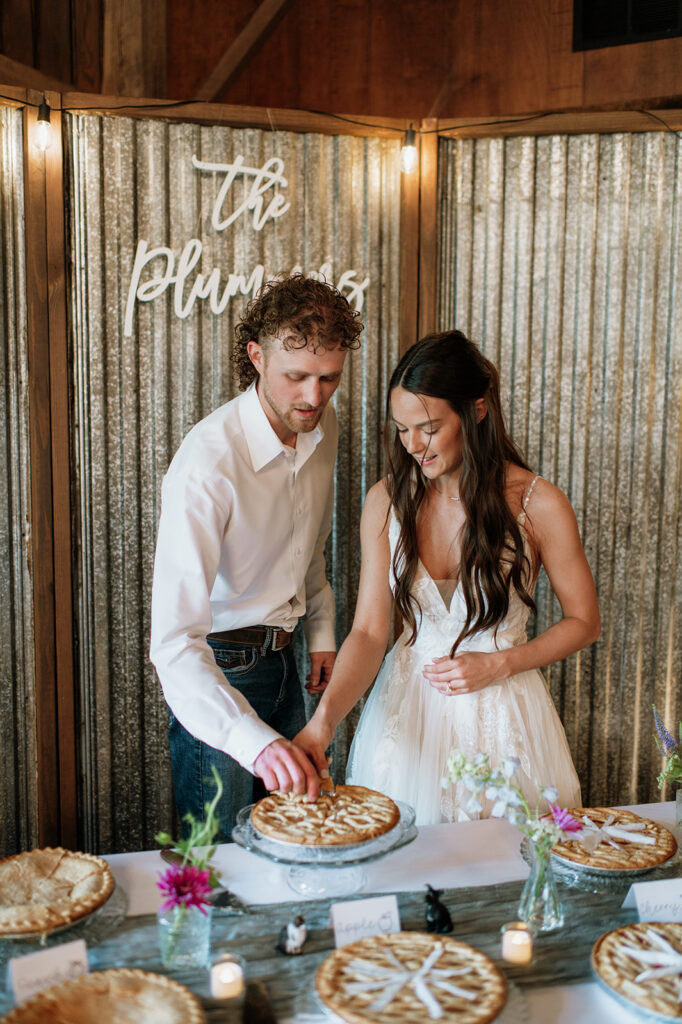 Bride and groom cutting a pie together at their reception instead of a traditional wedding cake.