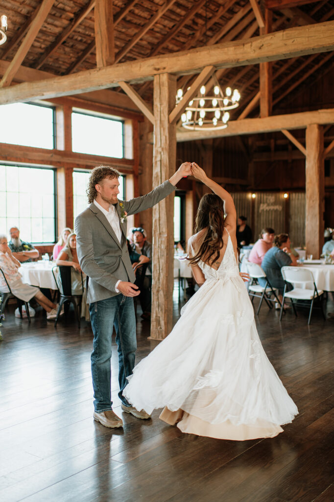 Groom twirling bride on the dance floor during their first dance inside the barn at 5C Farms.