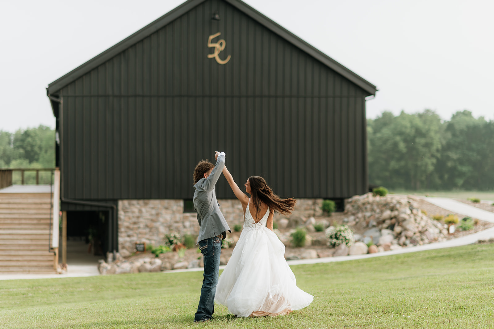 Groom twirling bride on the lawn in front of the barn at 5C Farms.