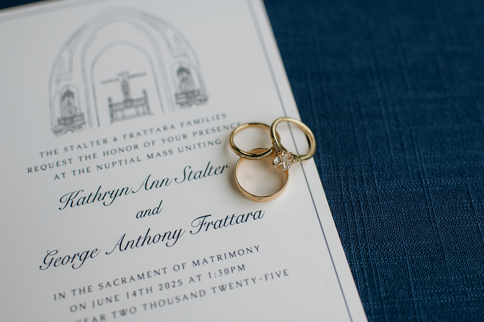 Gold wedding bands and diamond engagement ring resting on the couple’s invitation card of their Notre Dame wedding