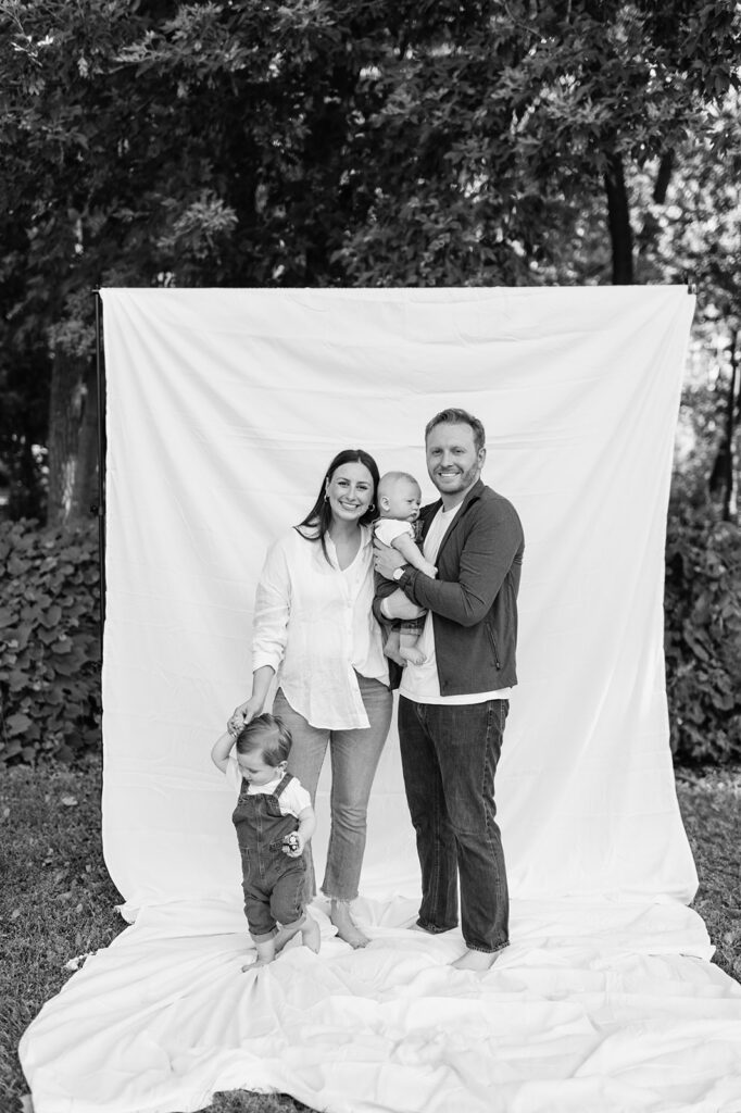 Family of four smiling together in front of a white sheet backdrop during their Chicago family photography session.
