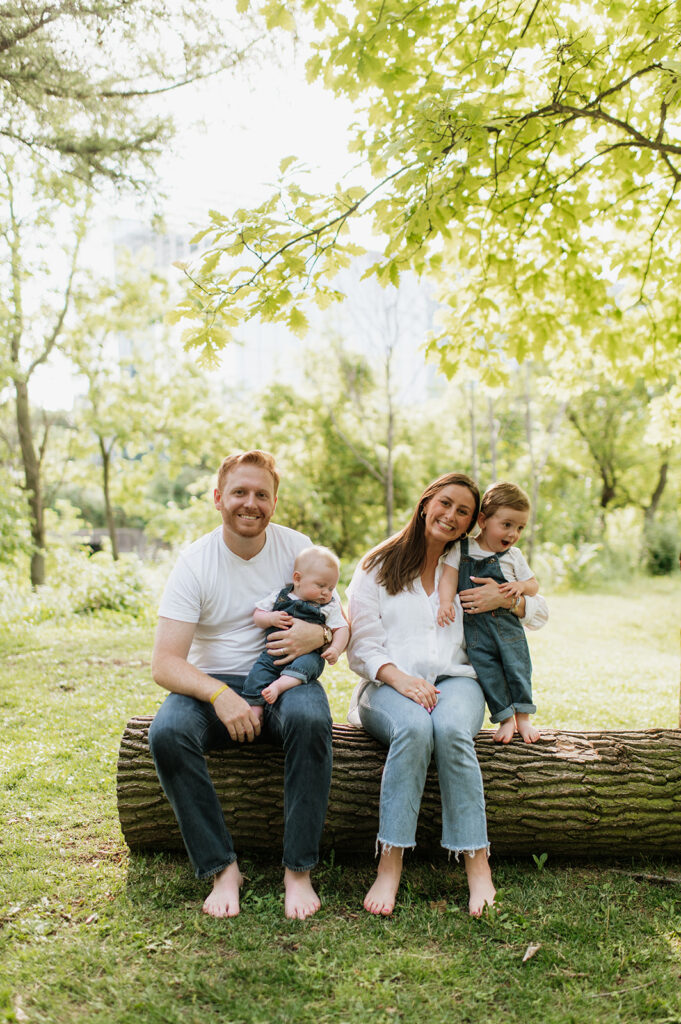 Family of four sitting on a log during their simple outdoor Chicago family photography session