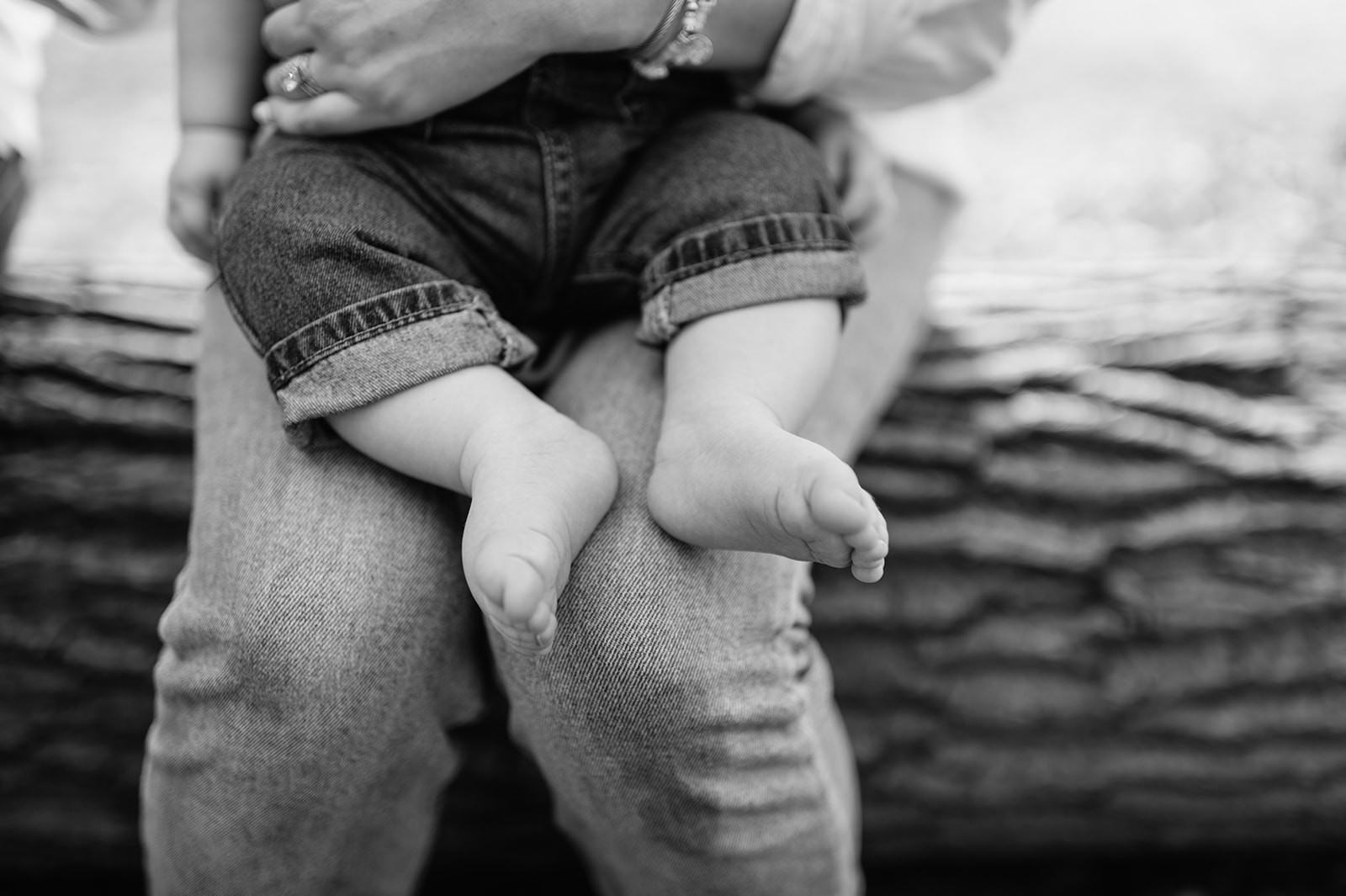 Close up black and white photo of a baby sitting on his mothers lap