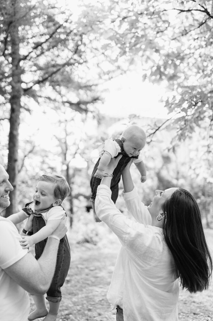 Black and white photo of parents holding their two young sons up in the air during their simple outdoor Chicago family photography session