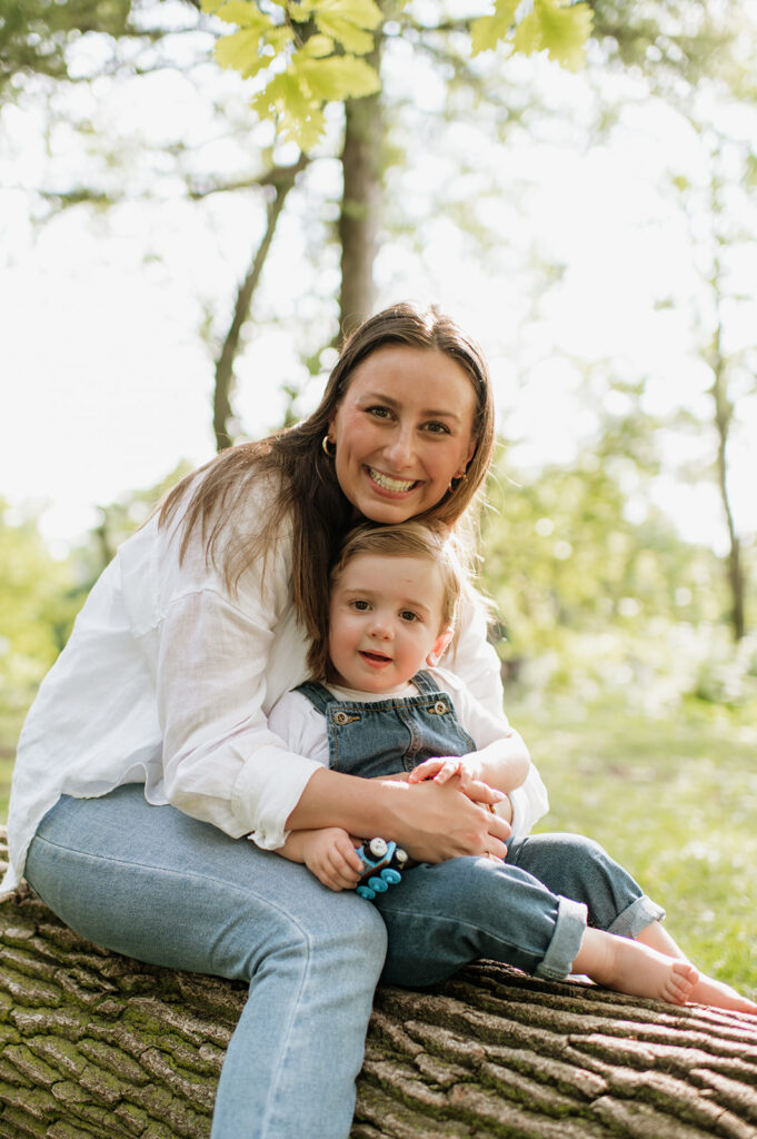 Mom and toddler son sitting on a log during their simple outdoor Chicago family photography session