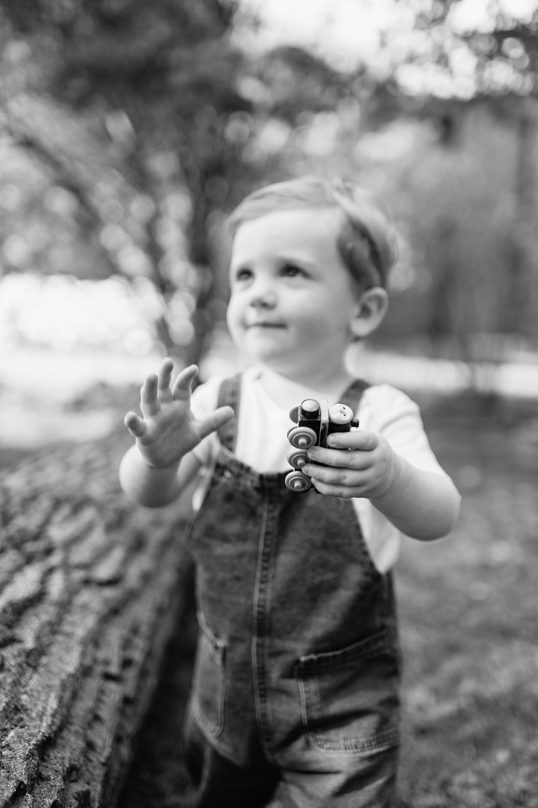 Black and white photo of a boy playing with a toy car outside
