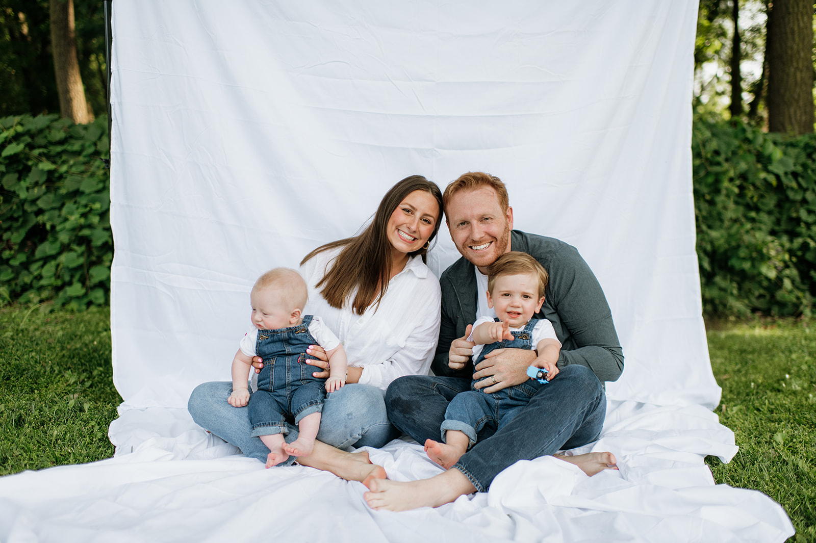 Family of four posing with a simple white sheet backdrop for their outdoor Chicago family photography session