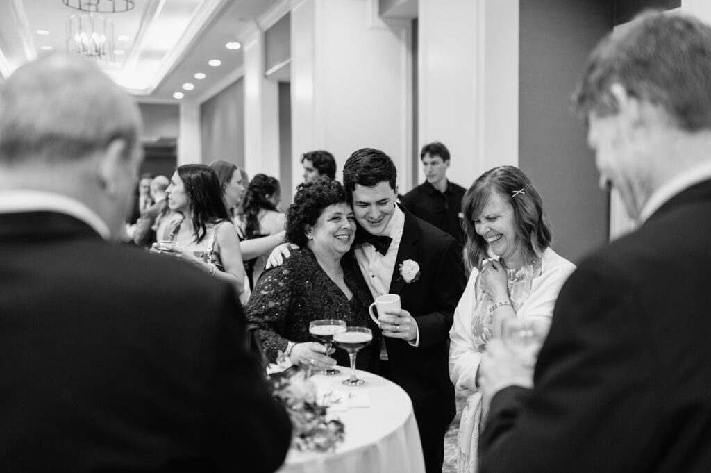 Black and white photo of the groom mingling during cocktail hour