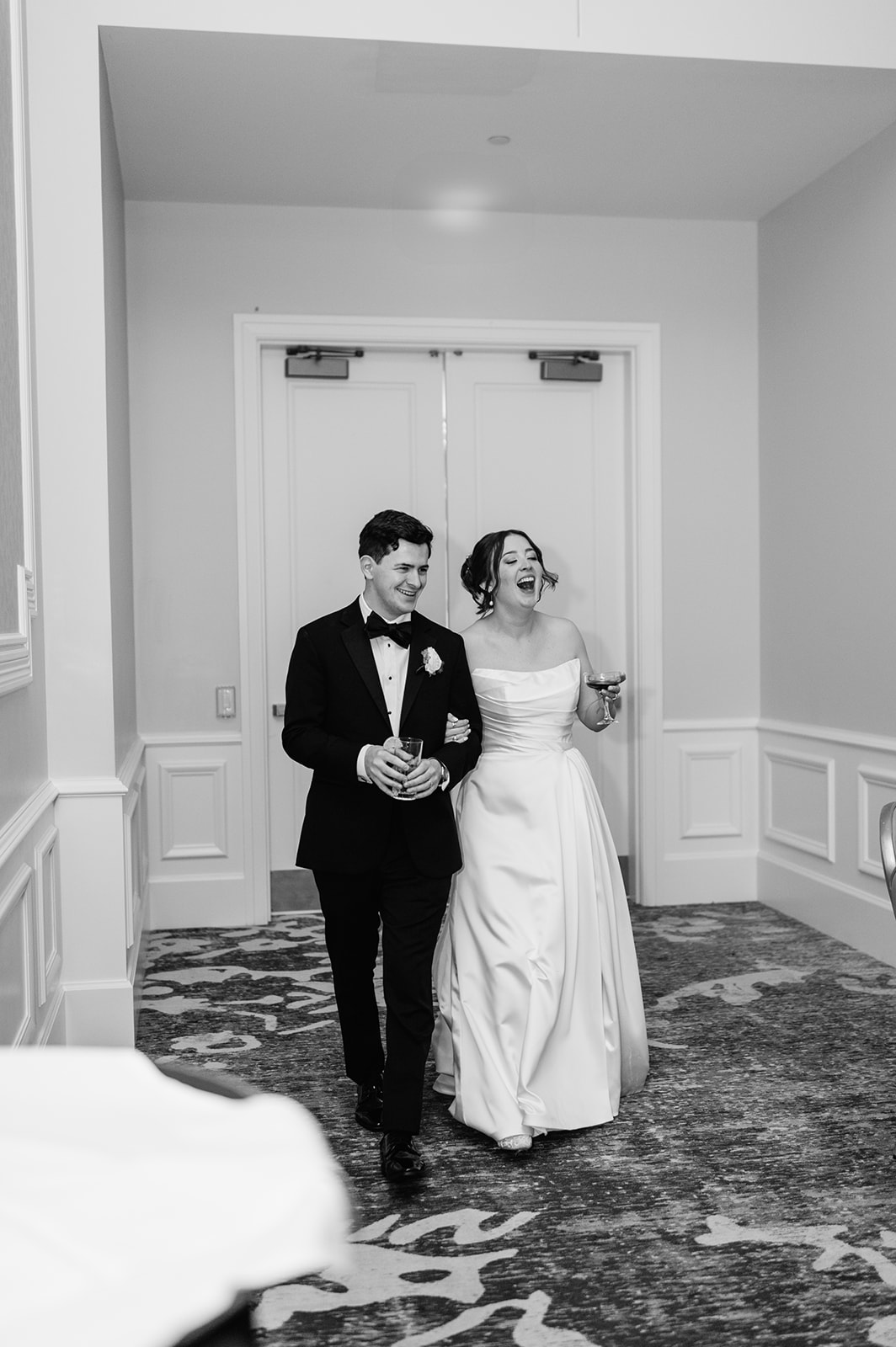 Black and white photo of a bride and groom smiling in awe of their wedding reception set up