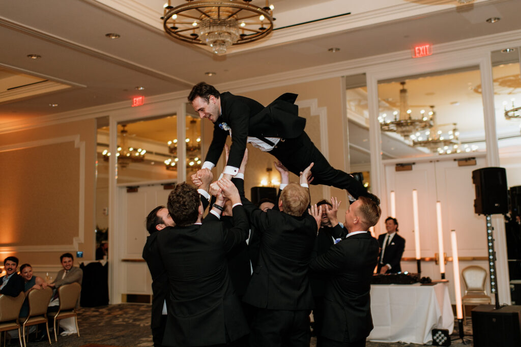 Groomsmen toss another groomsmen into the air during open dancing at the Smith Ballroom.