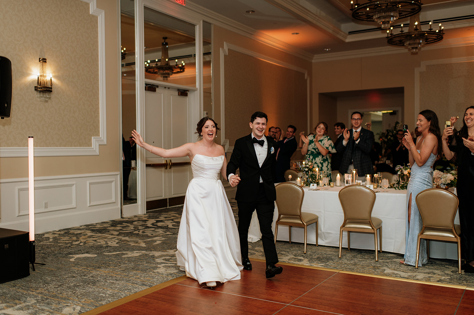 The bride and groom walk hand-in-hand into the Smith Ballroom before the reception begins.