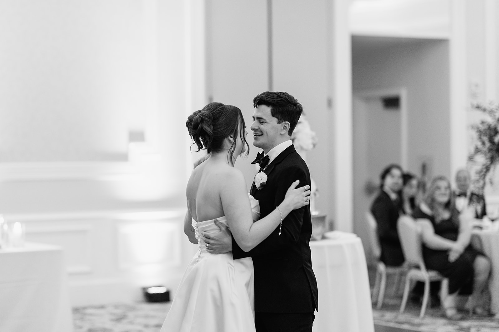 The bride and groom share a romantic first dance in the Smith Ballroom with their wedding cake in the background.