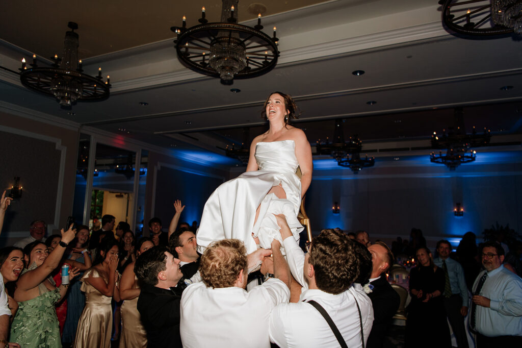 Guests lift the bride in chairs during their Smith Ballroom reception at The Morris Inn.