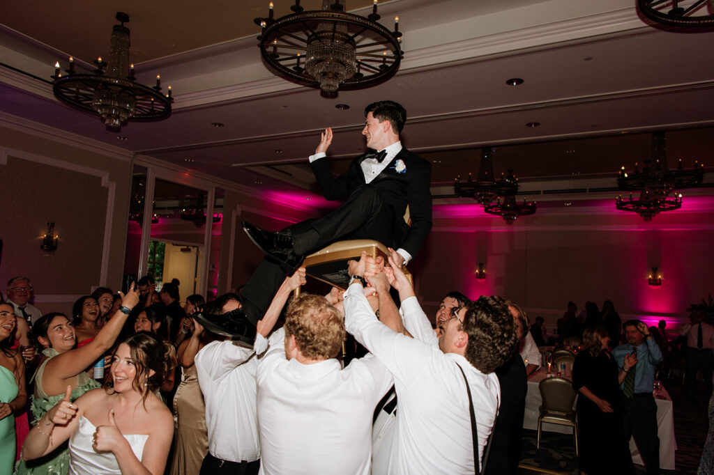 Guests lift the groom in chairs during their Smith Ballroom reception at The Morris Inn.