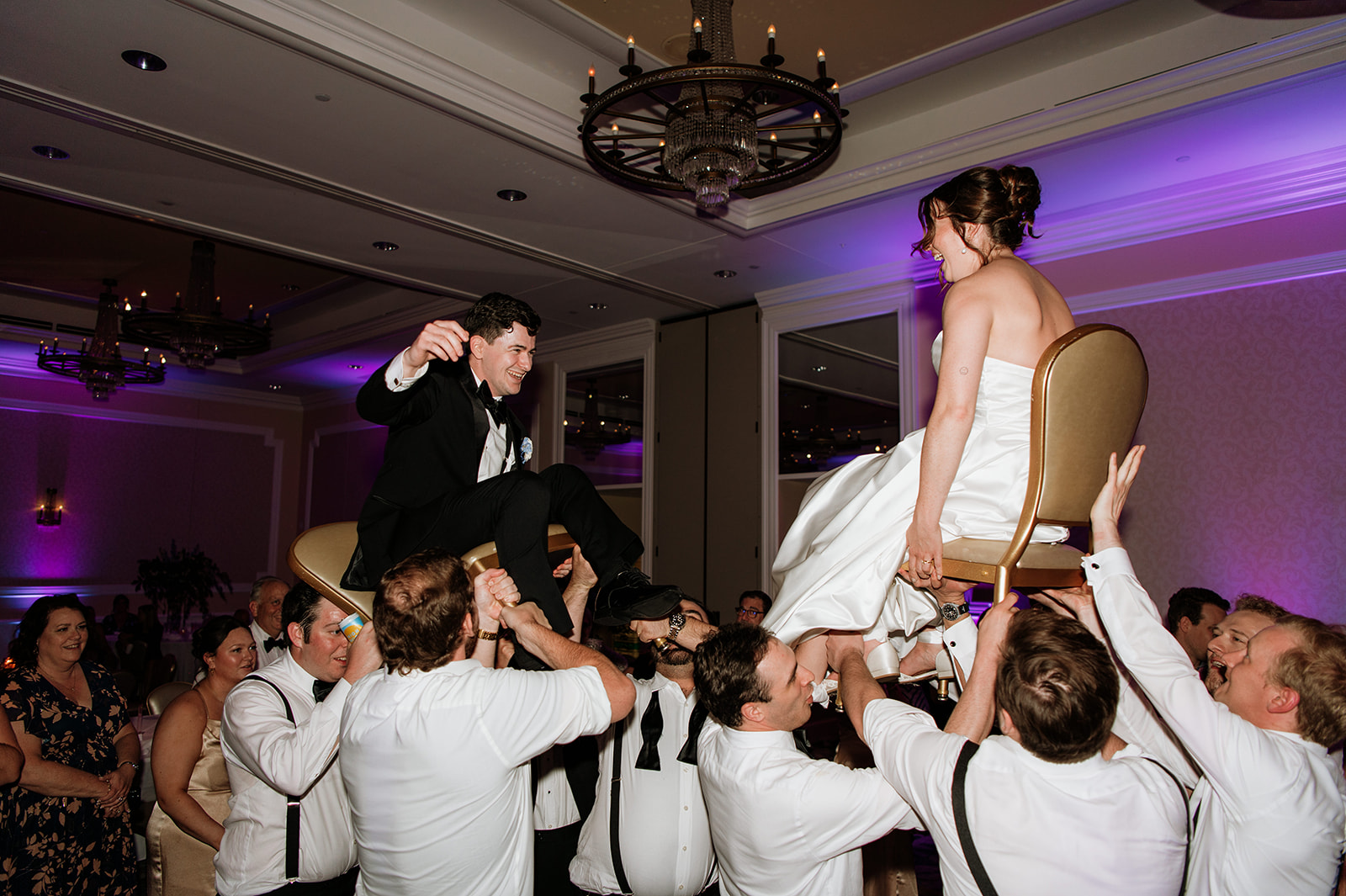 Guests lift the bride and groom in chairs during their Smith Ballroom reception at The Morris Inn.