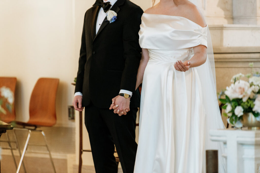 Close-up of bride and groom holding hands during their Notre Dame wedding ceremony.