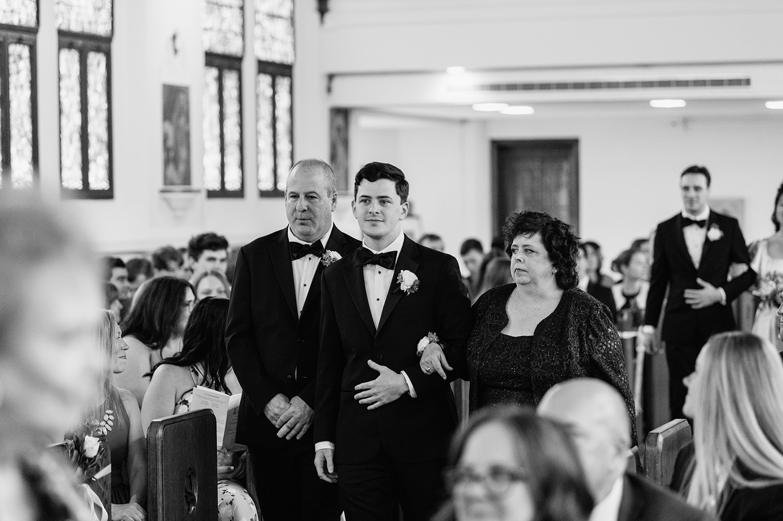 Groom walks down the aisle with his parents at The Holy Spirit Chapel during Notre Dame wedding ceremony.