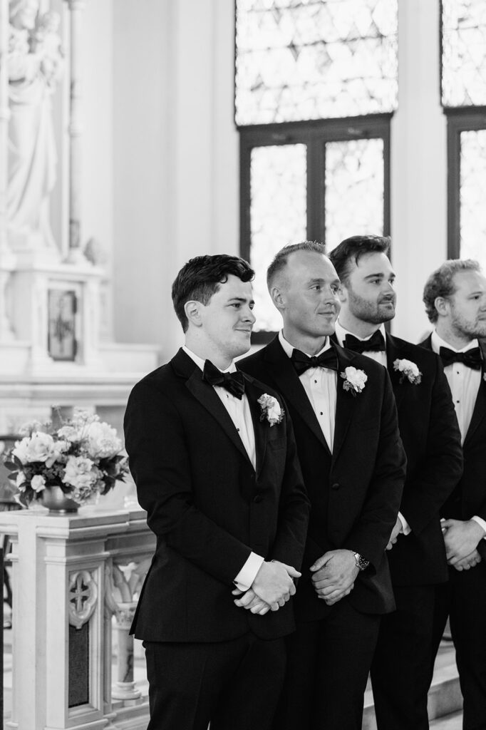 Groom smiles at the altar alongside groomsmen, waiting for the bride at Notre Dame wedding.