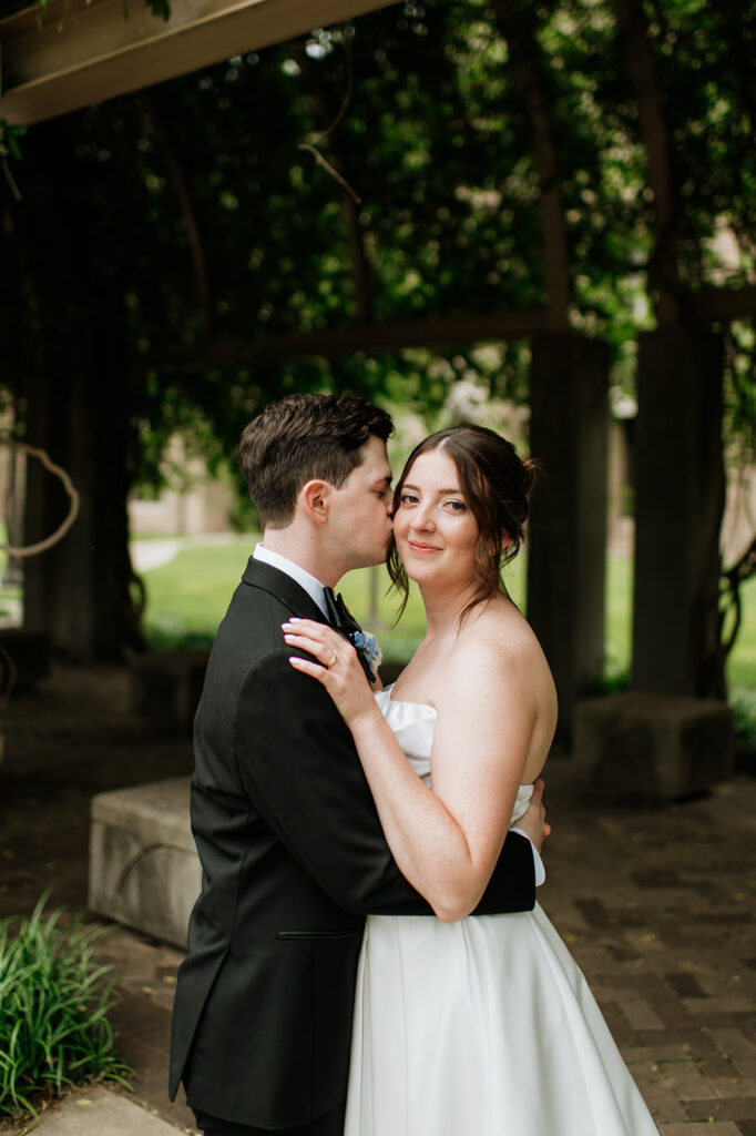 Close up shot of a groom kissing his brides cheek during their Notre Dame wedding portraits