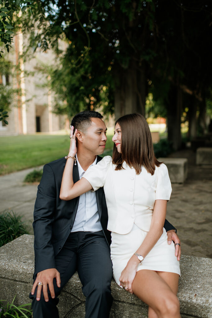 Close up shot of a couple sitting on the bench under a shaded archway at Notre Dame.