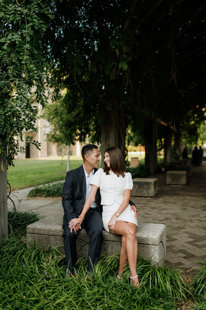Couple sharing a candid moment on the bench under a shaded archway at Notre Dame.