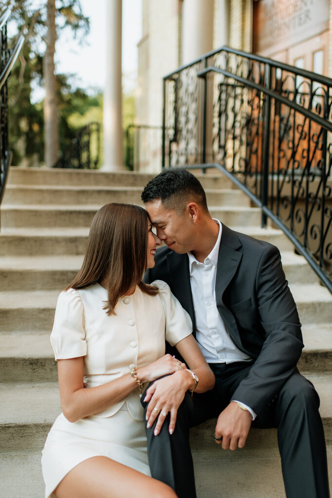 Couple sitting and touching noses on the staircase outside LaFortune during their University of Notre Dame engagement photos.