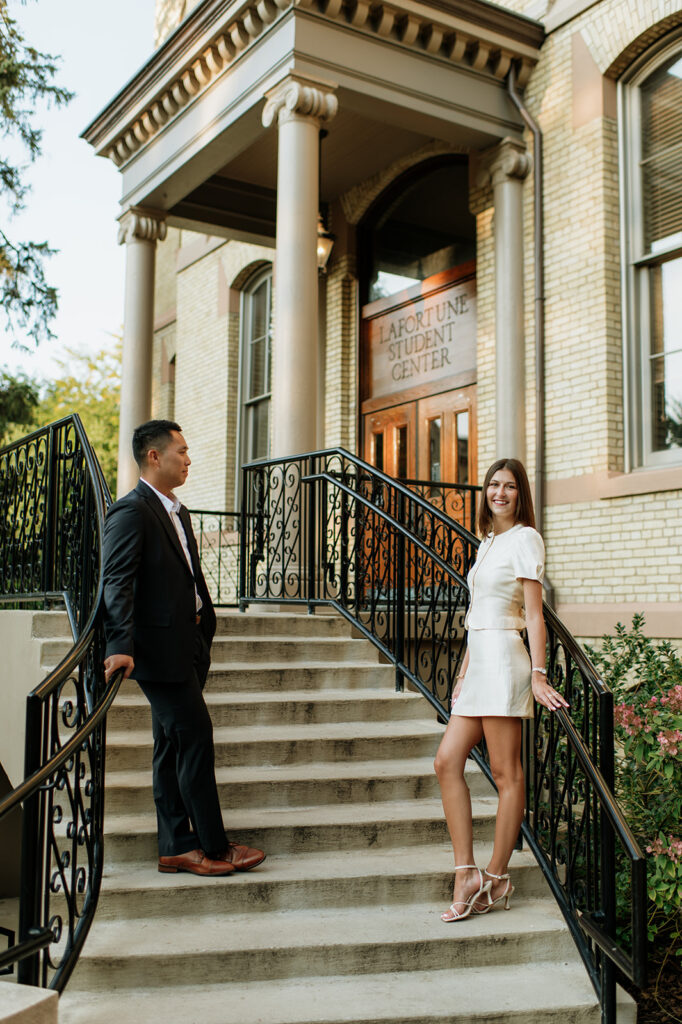 Couple posing on opposite sides of the staircase railings at LaFortune Student Center.
