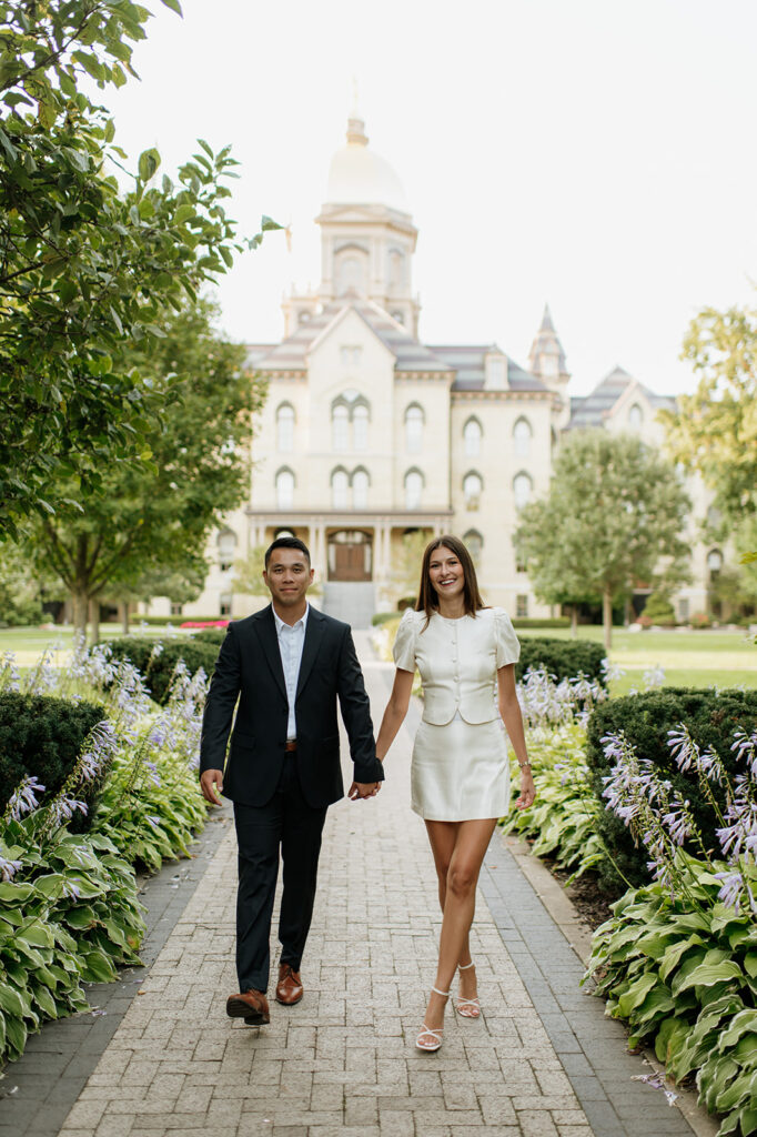 Couple walking hand in hand with the Main Building and golden dome in the background.