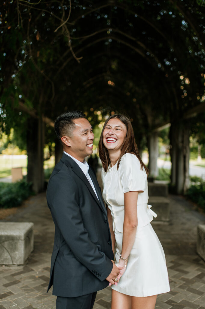 Couple holding hands and laughing under the vine tunnel at Notre Dame.