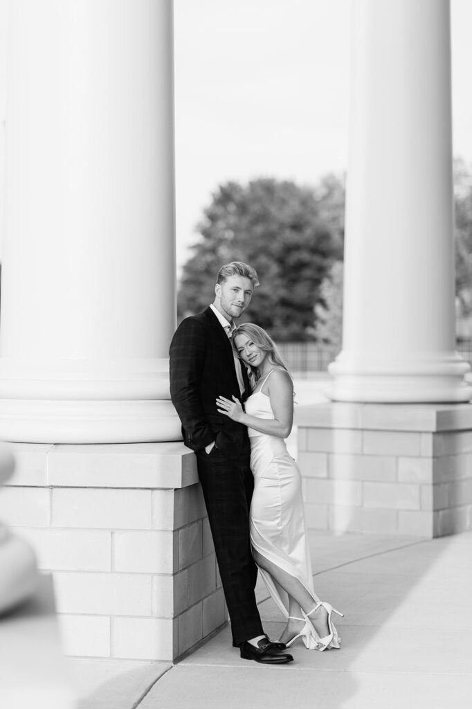 Romantic black and white photo of the couple leaning together by the courthouse columns