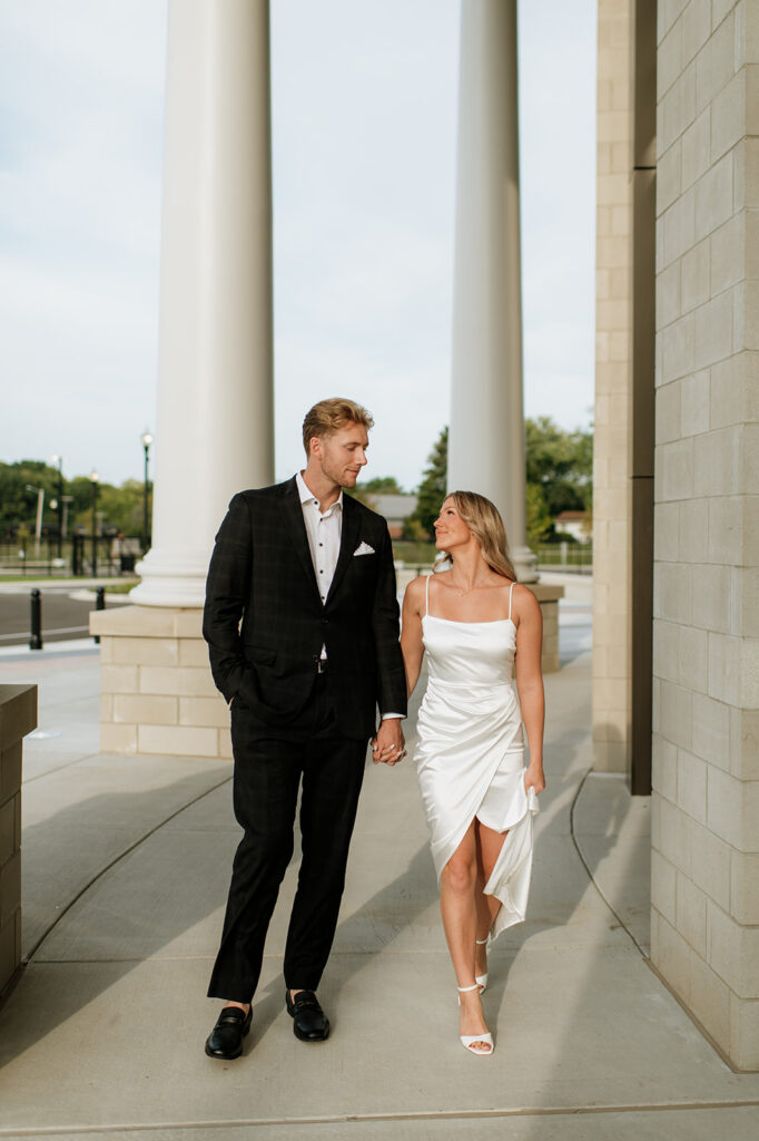 Couple walking hands in hand at the courthouse columns in Goshen, Indiana