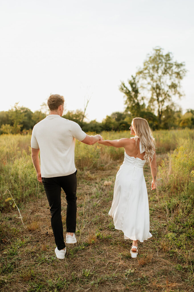 Couple walking hand in hand through the field during sunset in Goshen, Indiana