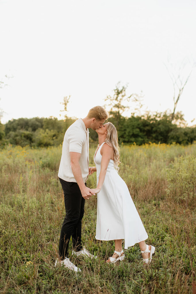 Couple kissing each other in the tall grass at golden hour