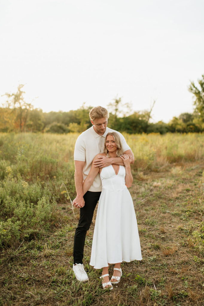 Couple standing in a grassy field during golden hour for their Goshen, Indiana engagement photos