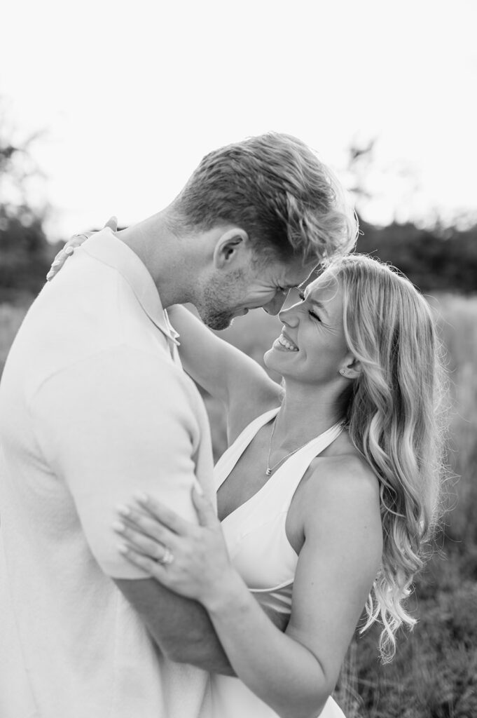Close up shot of a could touching noses and laughing together in a field at golden hour