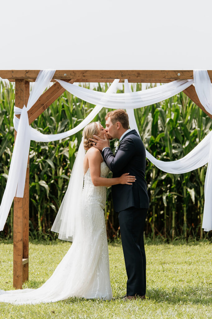 Bride and groom sharing first kiss as newlyweds at Rock Run Creek Barn ceremony.