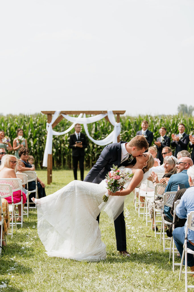 Bride and groom kissing at the end of the aisle after outdoor ceremony at Rock Run Creek Barn.