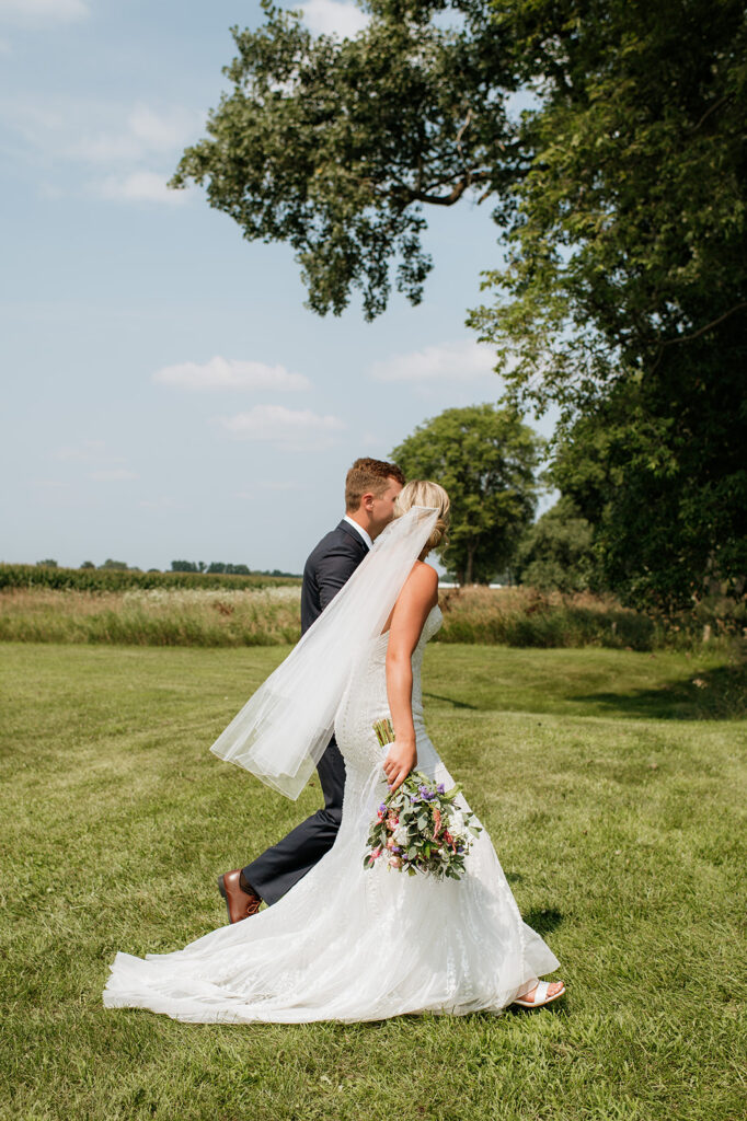 Couple walking through the field together after their Rock Run Creek Barn wedding ceremony.