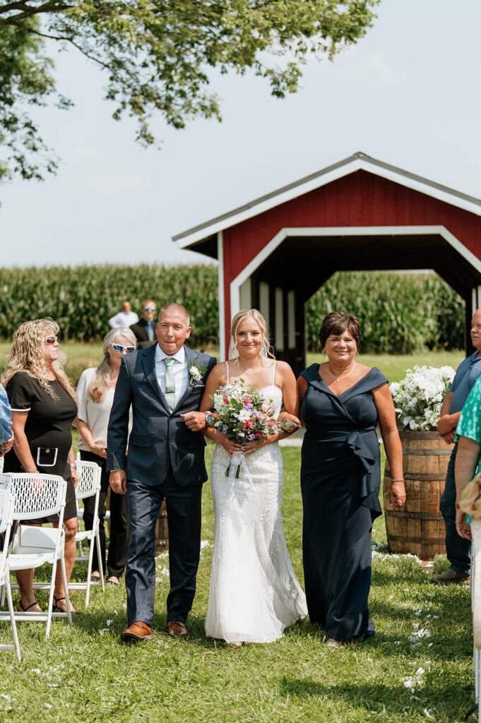 Bride walking down the aisle with her parents at Rock Run Creek Barn wedding ceremony.