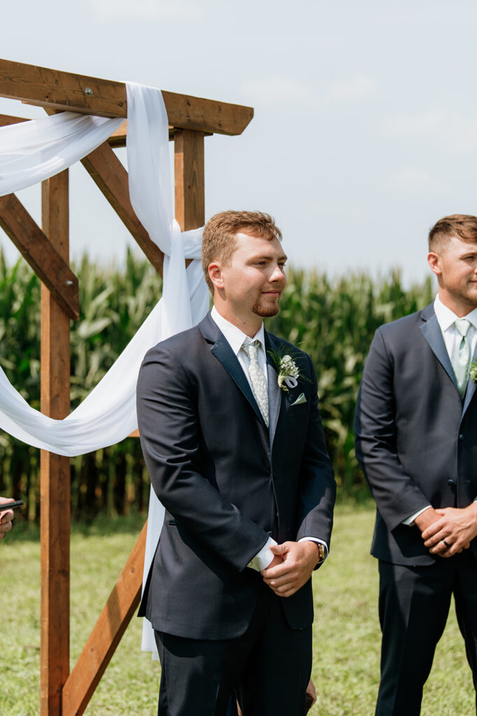 Groom watching bride walk down the aisle during outdoor ceremony at Rock Run Creek Barn.