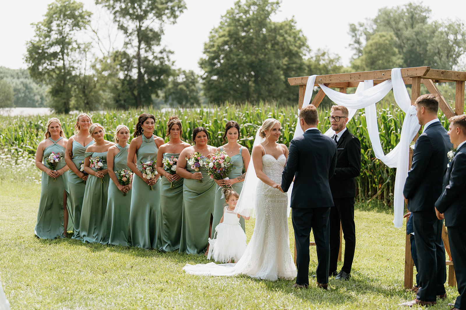 Couple holding hands under wooden arch draped in white fabric at Rock Run Creek Barn.