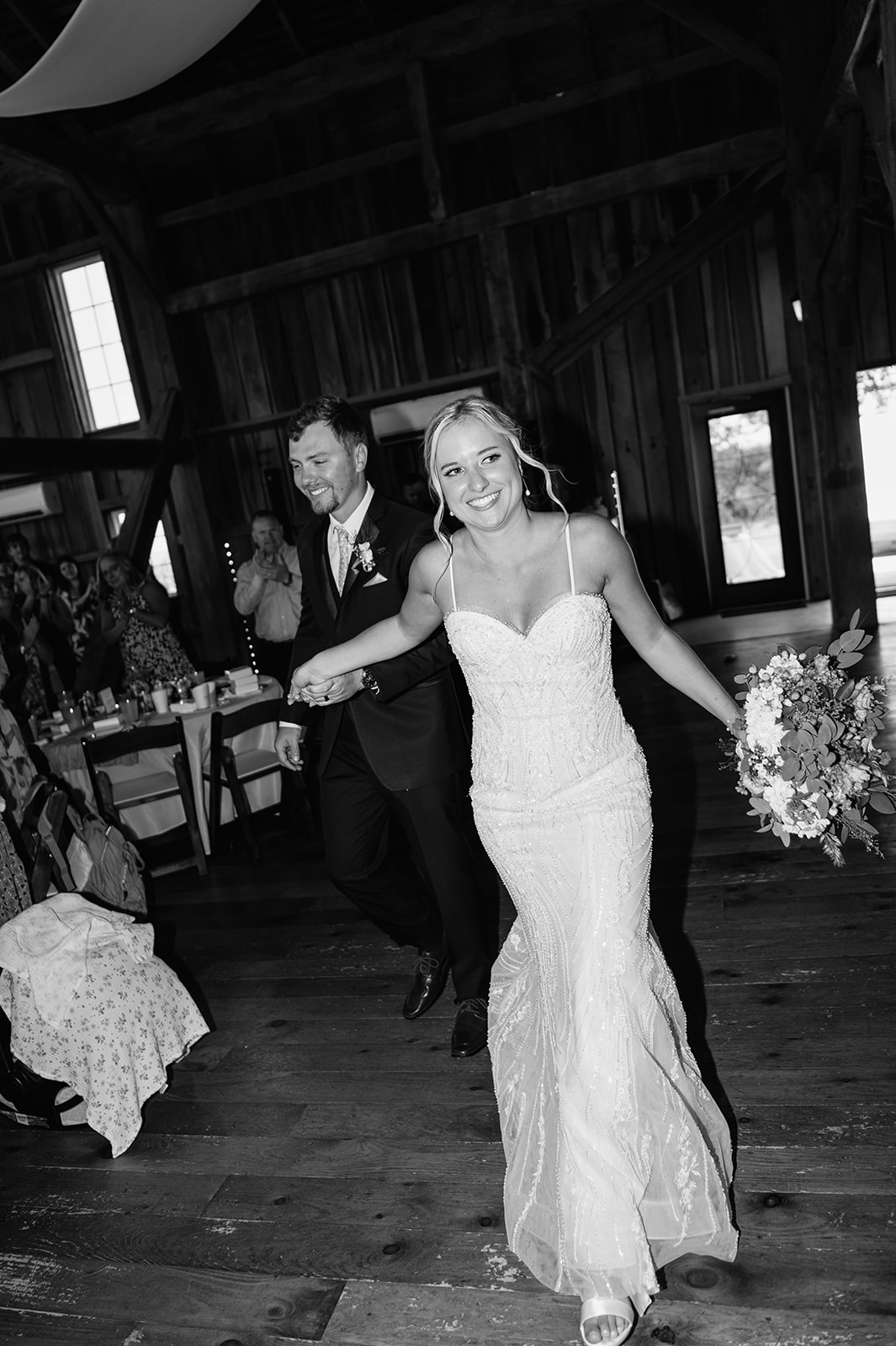 Bride and groom entering their Rock Run Creek Barn wedding reception with cheers from guests.