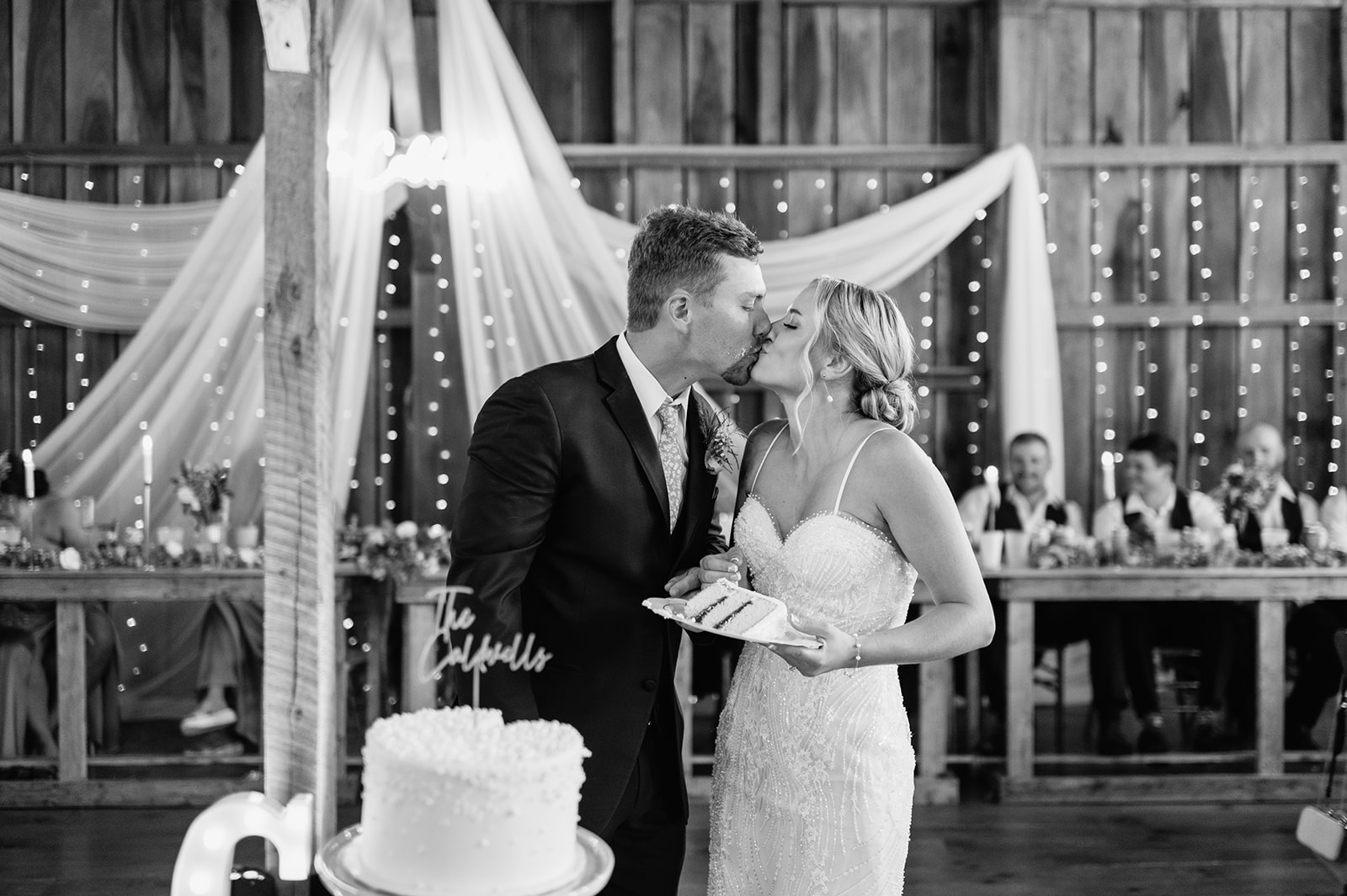 Bride and groom kissing after cake cutting at Rock Run Creek Barn wedding reception.