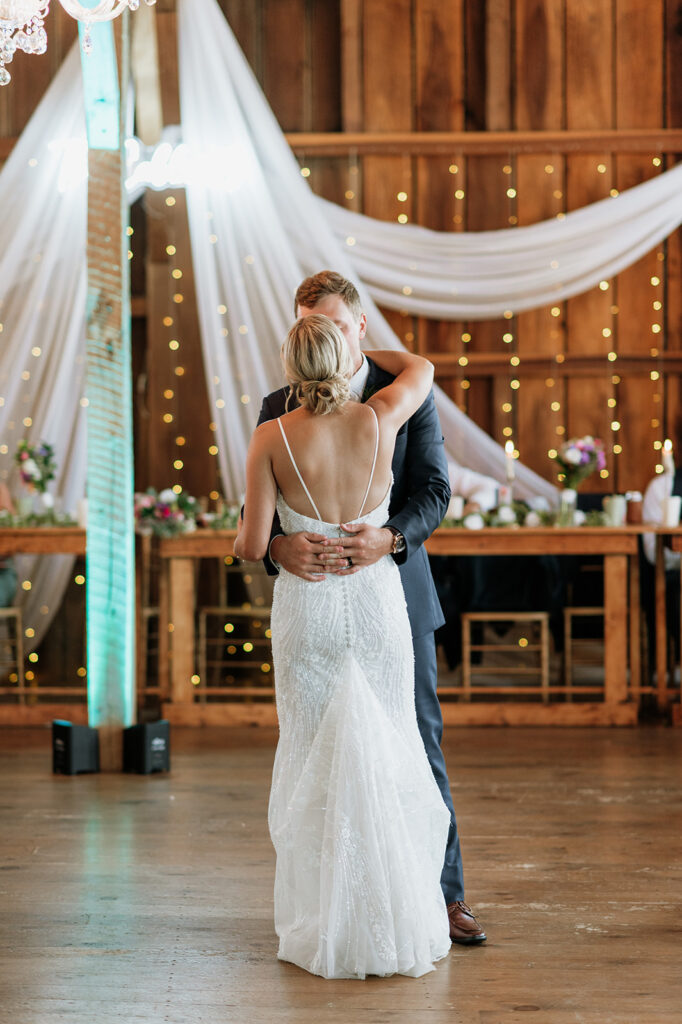 Bride and groom embracing during first dance at Rock Run Creek Barn wedding reception.